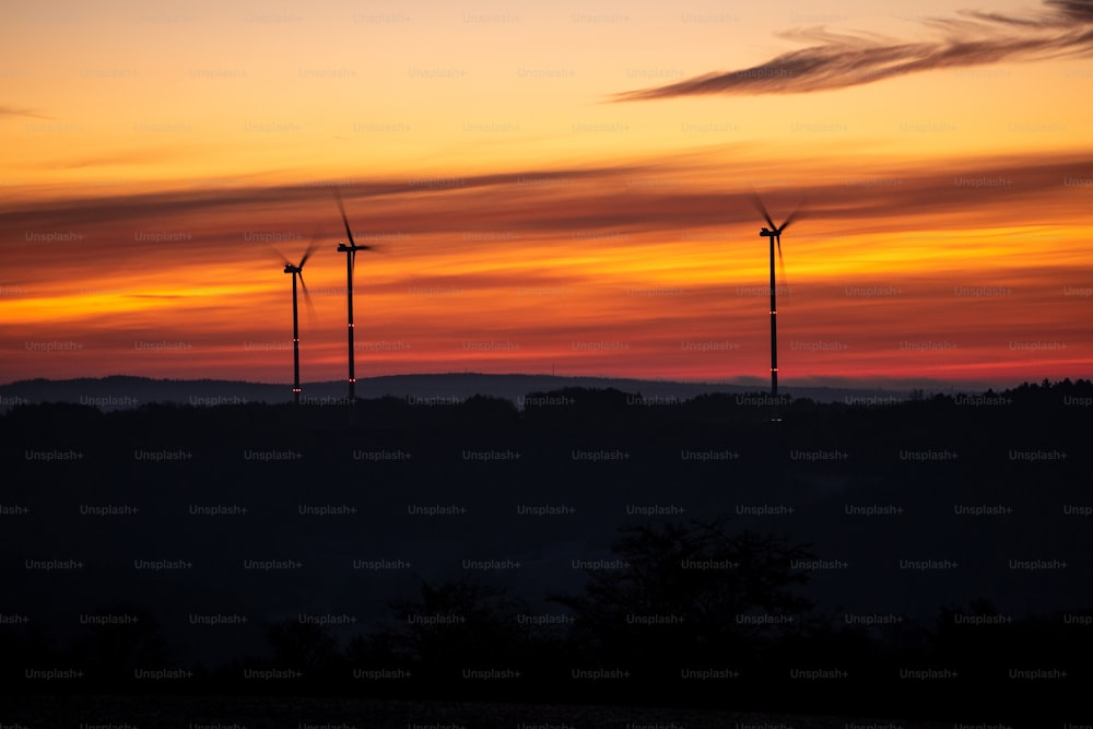 Un groupe de moulins à vent se dessine contre un coucher de soleil