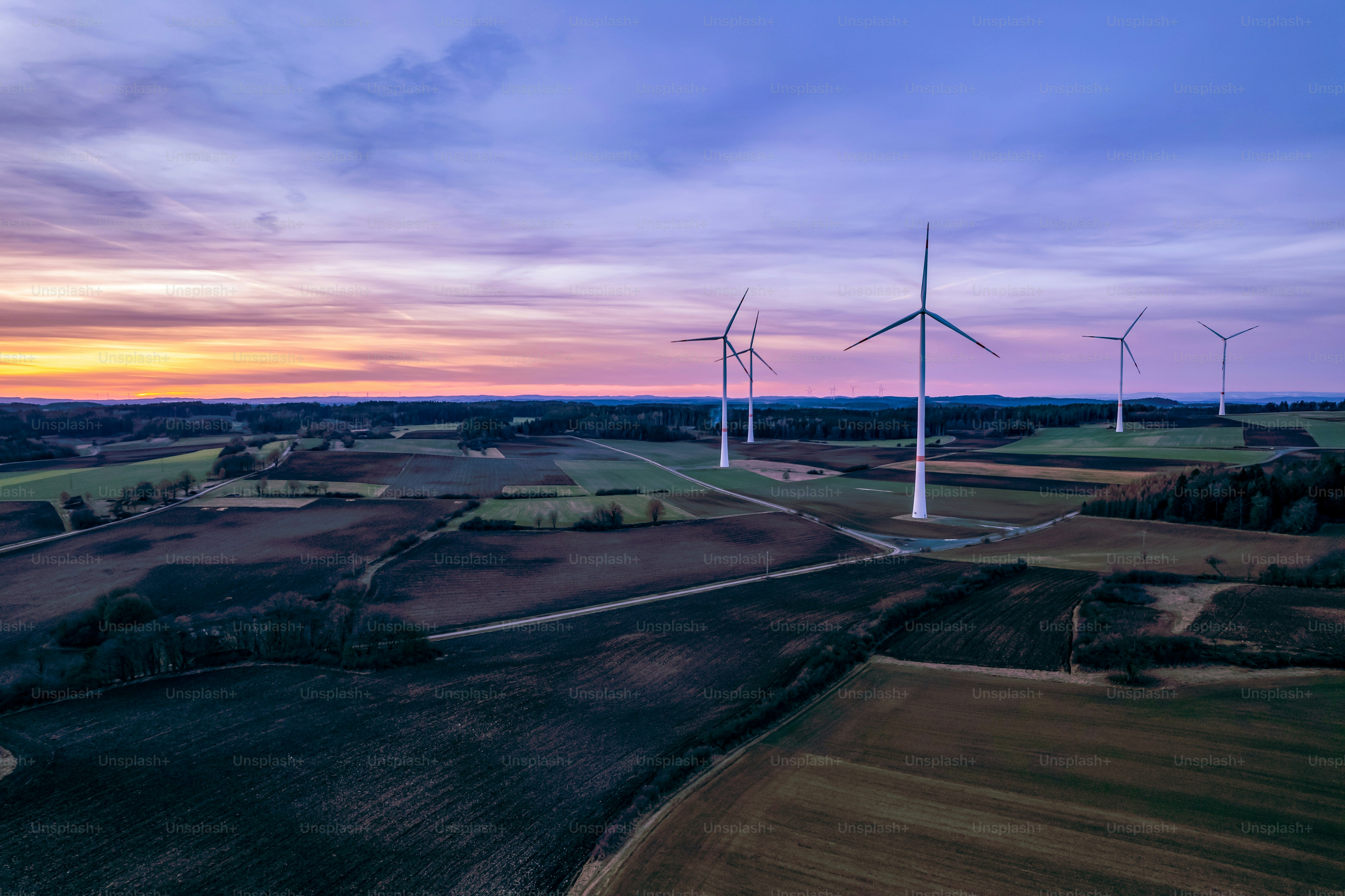 a group of windmills in a field at sunset