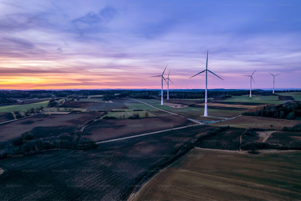 a group of windmills in a field at sunset