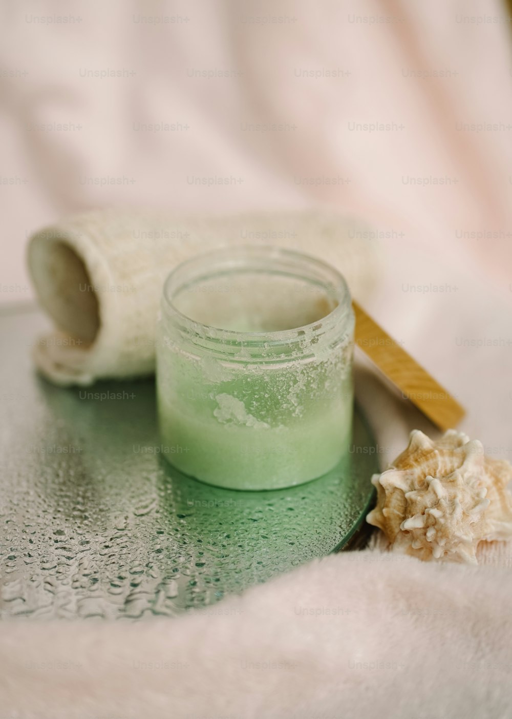 a jar of green liquid next to a wooden brush