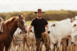 Un uomo con un cappello da cowboy sta guidando una mandria di bestiame