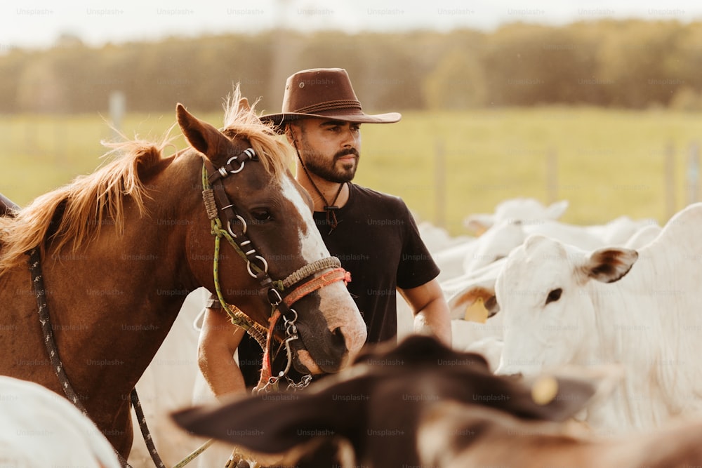 um homem em um chapéu de cowboy de pé ao lado de um cavalo