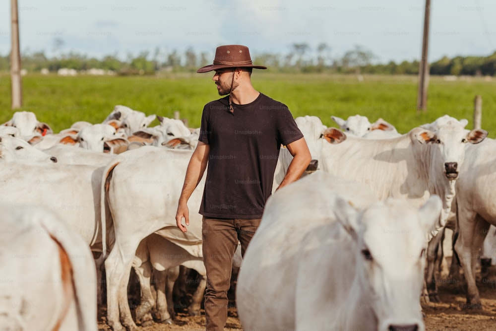 Un hombre parado frente a una manada de ganado