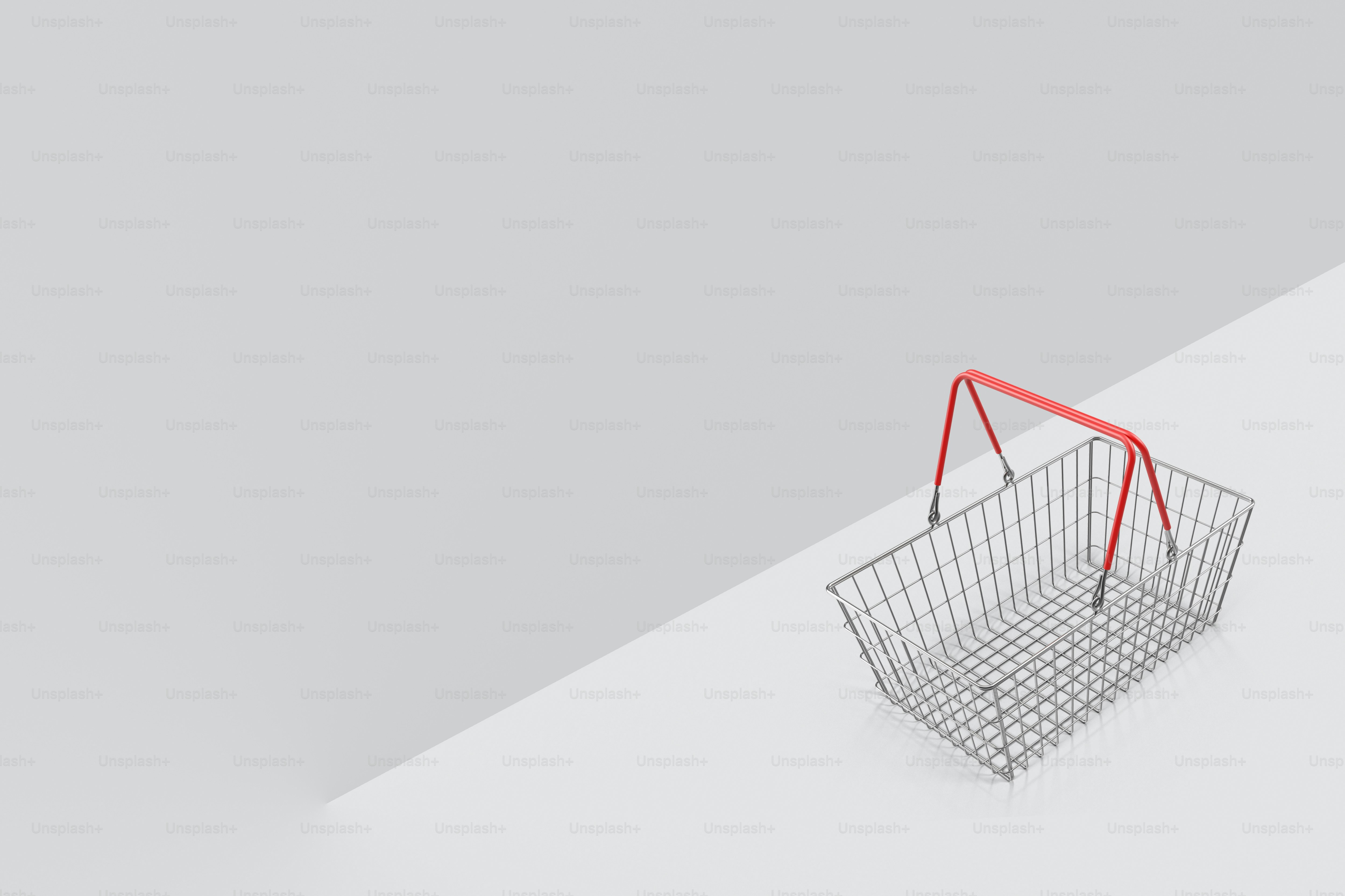 a shopping basket with a red handle on a white surface