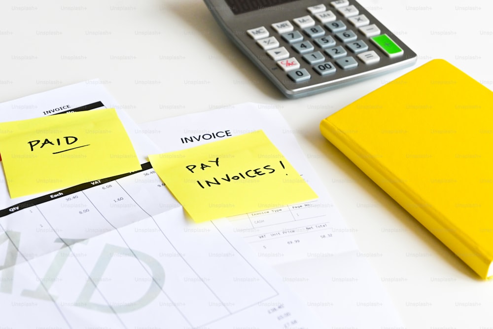 Una nota adhesiva amarilla sentada encima de un escritorio junto a una calculadora