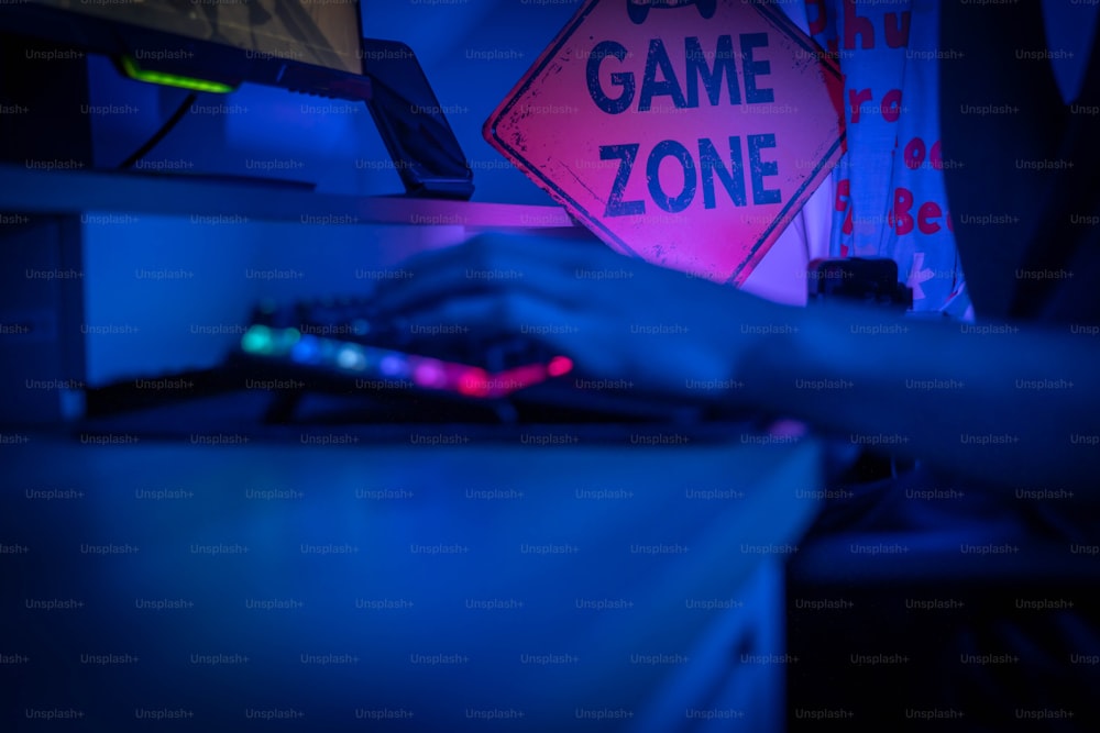 a person typing on a keyboard in front of a game zone sign