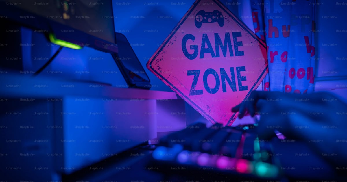 A game zone sign sitting on top of a computer desk photo – Gaming setup ...