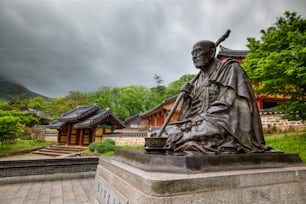 uma estátua de um homem segurando um cajado na frente de um edifício