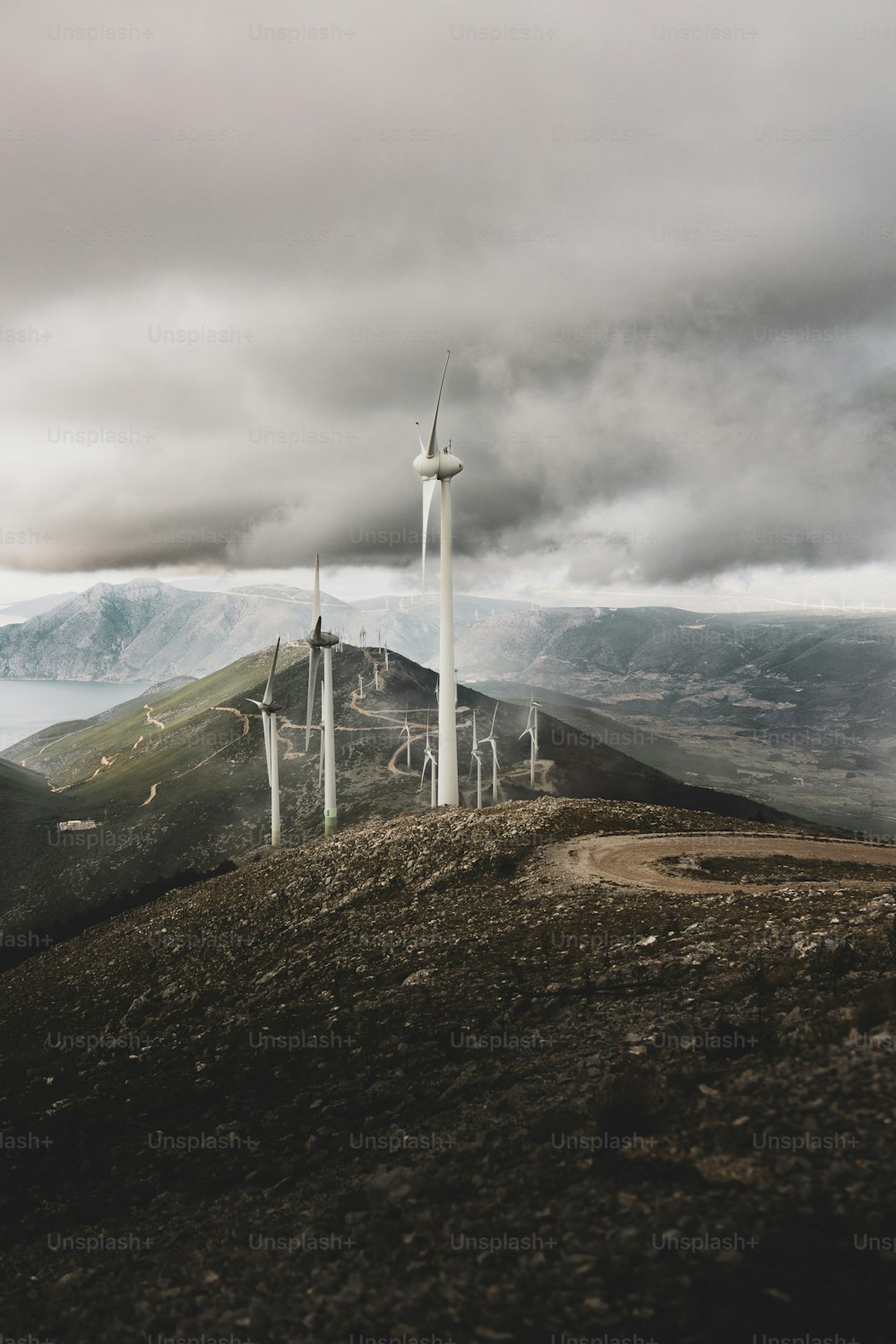 a group of windmills on a hill under a cloudy sky