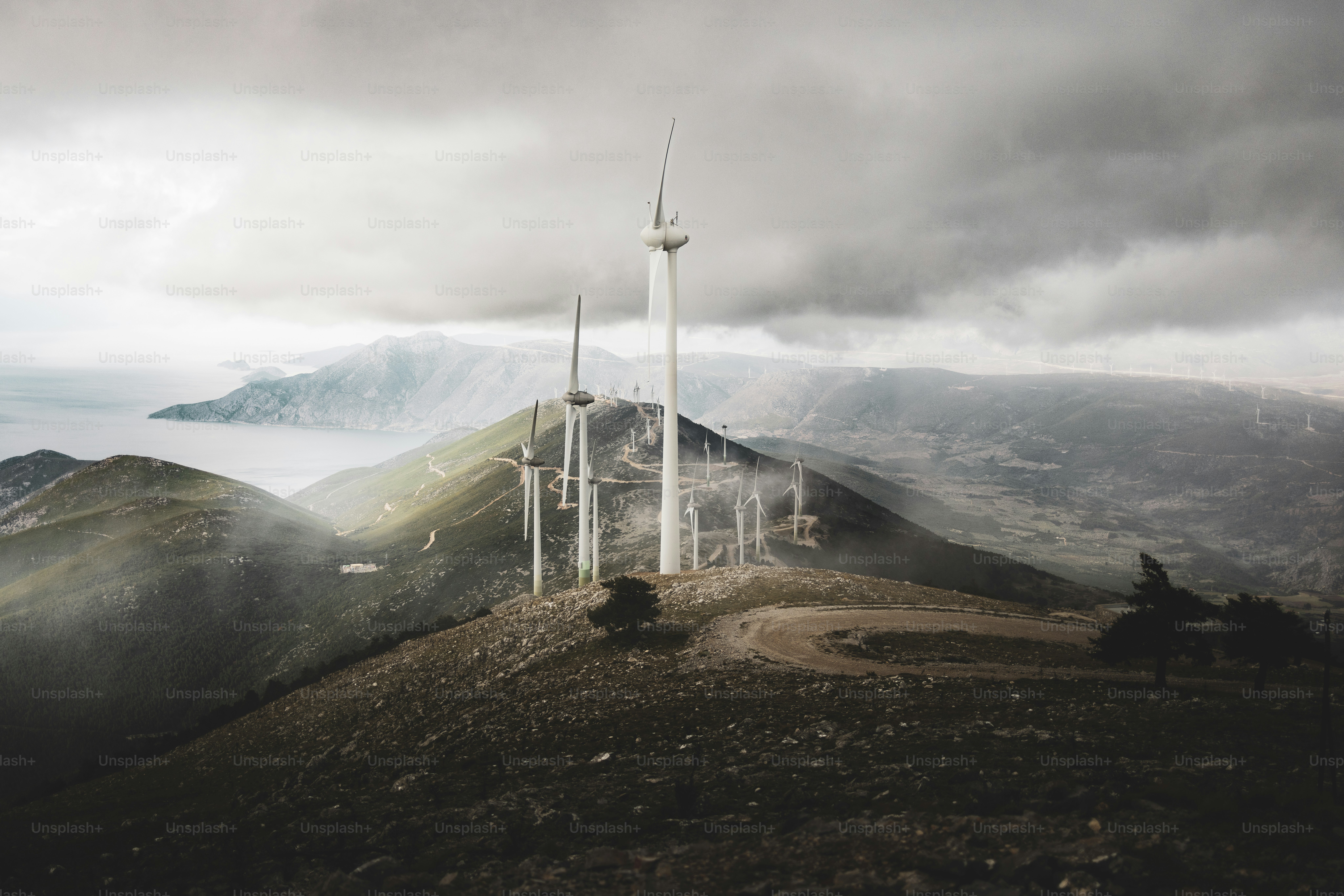 a wind farm on top of a mountain under a cloudy sky
