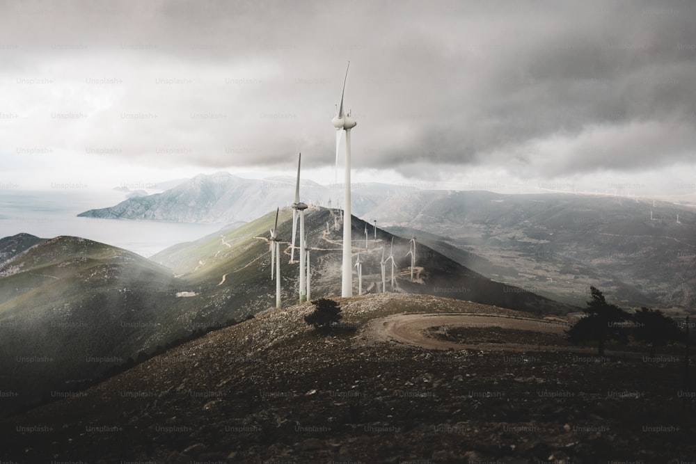a wind farm on top of a mountain under a cloudy sky