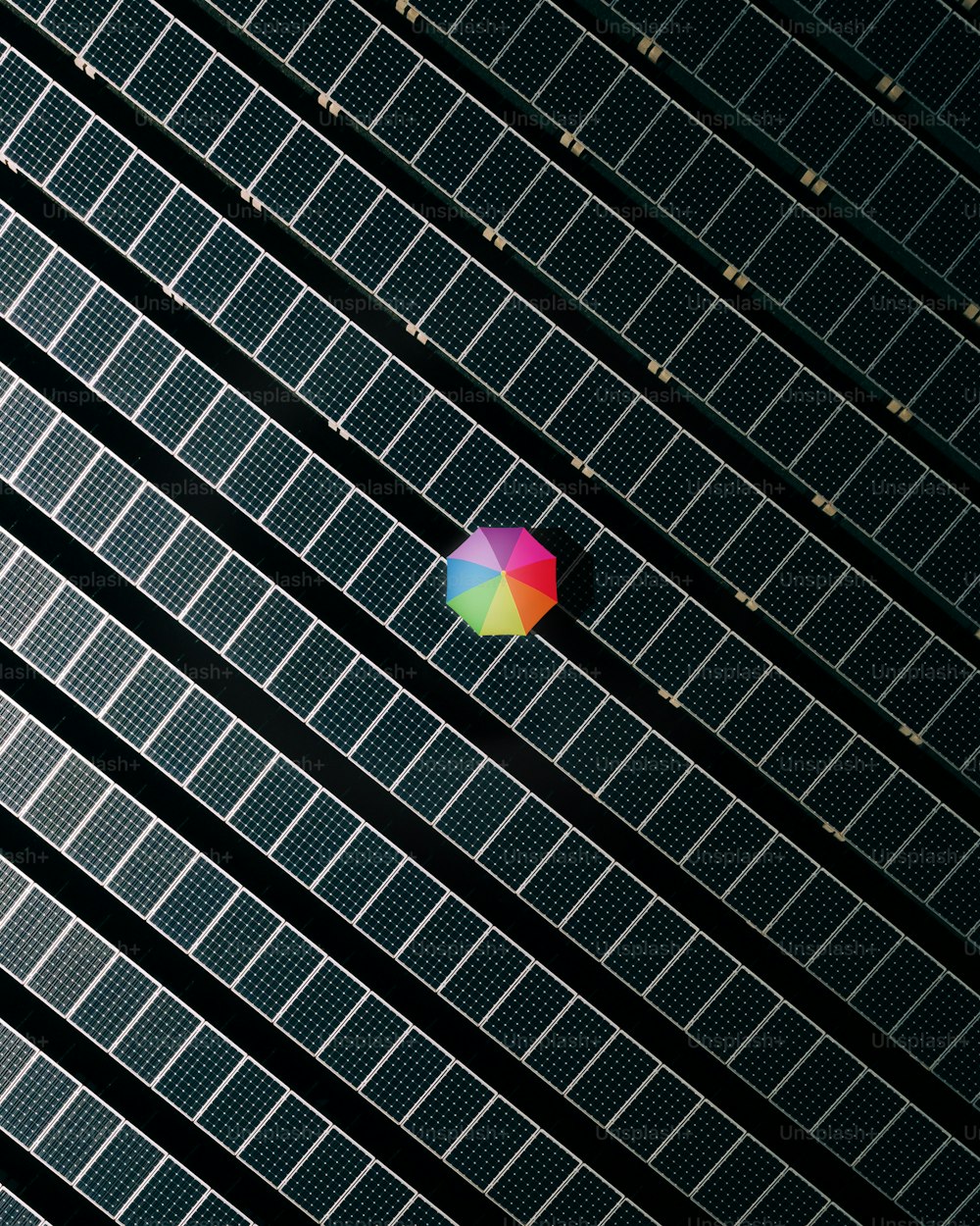 Un paraguas de colores sentado encima de un panel solar