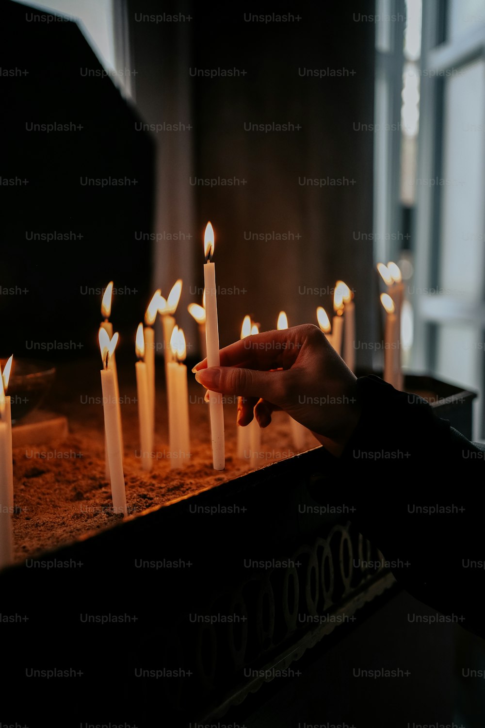 a person holding a lit candle in front of a cake