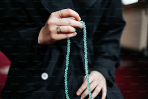 a woman is holding a green beaded necklace