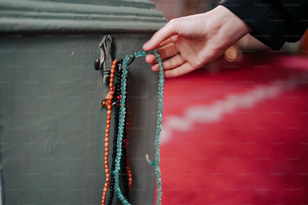 une personne tenant un collier de perles sur un mur