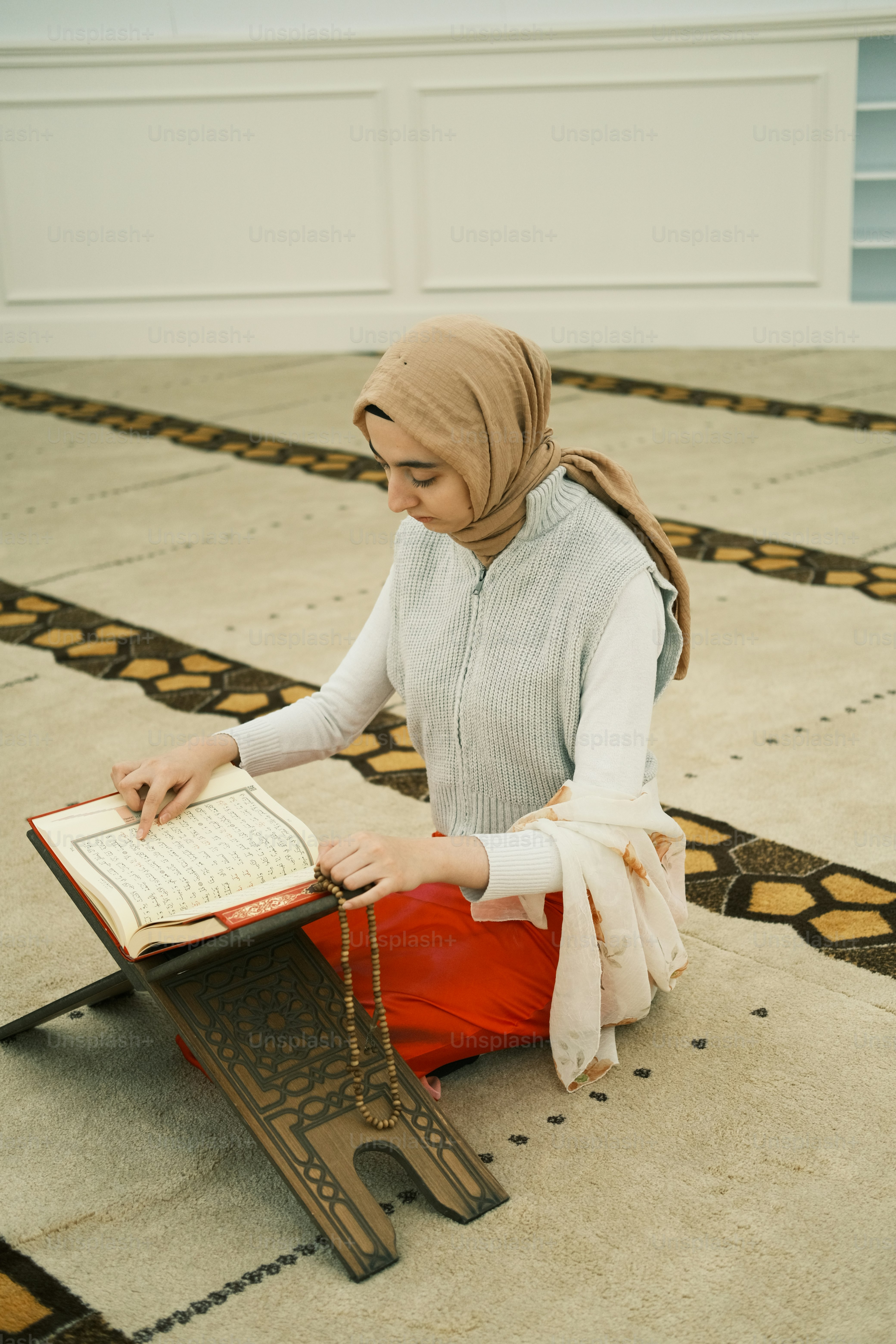 A woman sitting on the floor reading a book photo – Mosque Image on ...