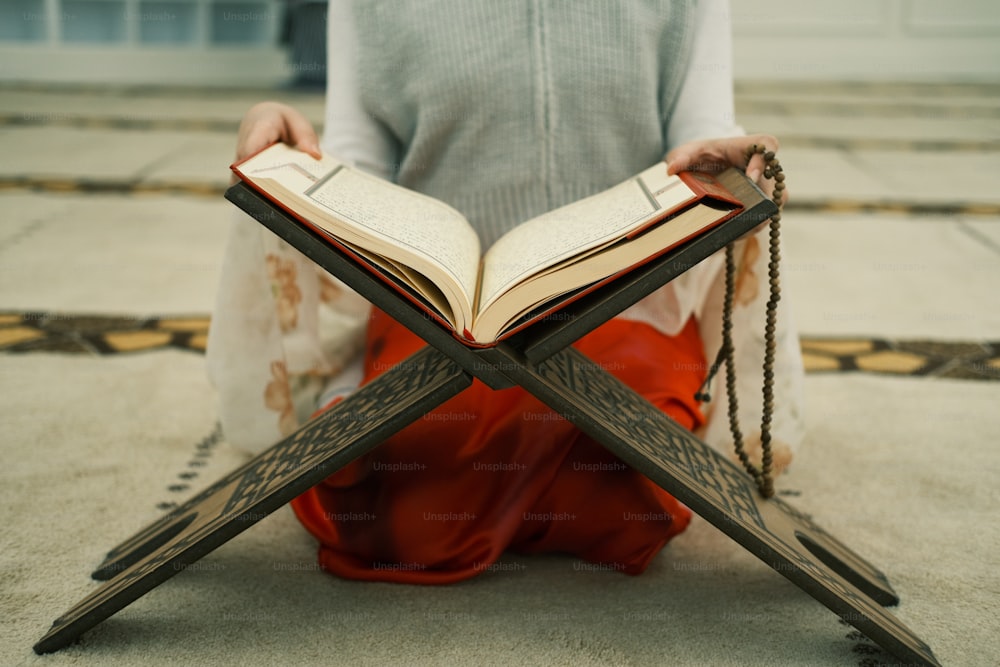una donna seduta sul pavimento che legge un libro