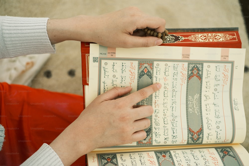 a person is holding a book with arabic writing on it