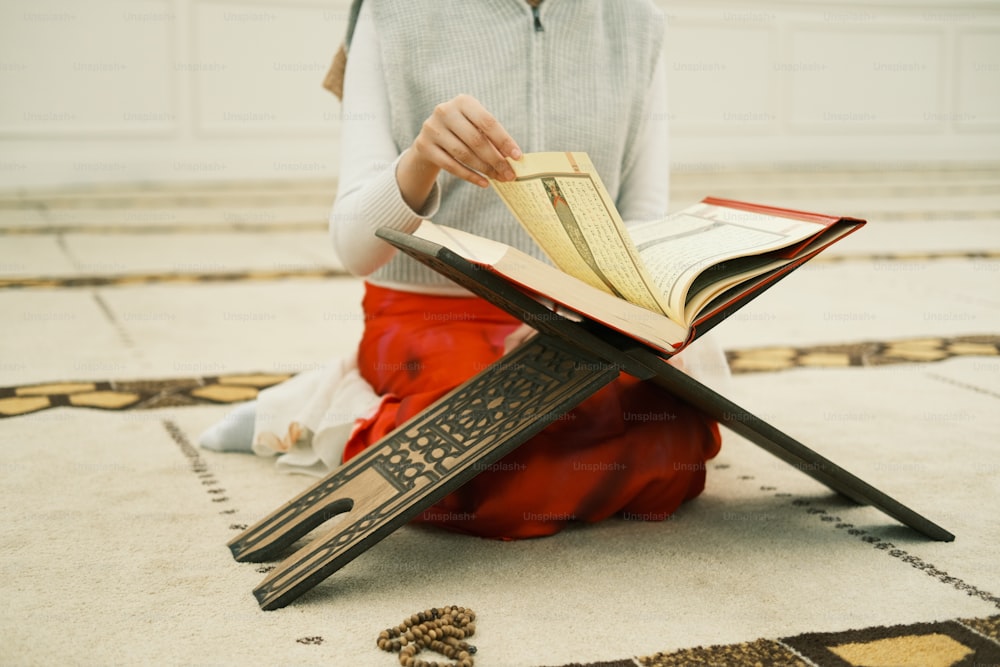 a little girl sitting on the floor reading a book