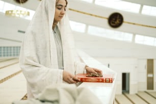a woman in a white robe holding a red book