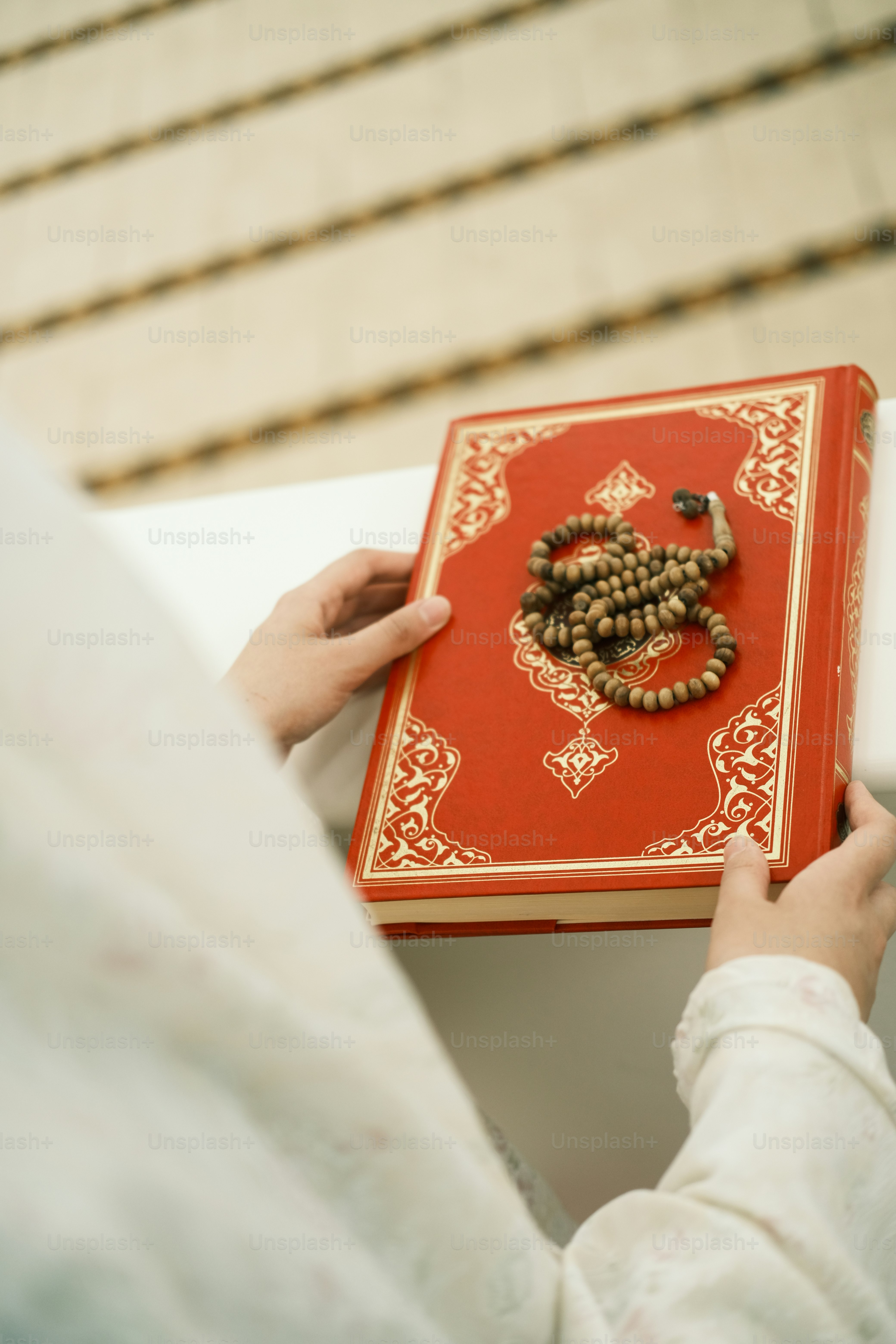 a person holding a red book with a rosary on it