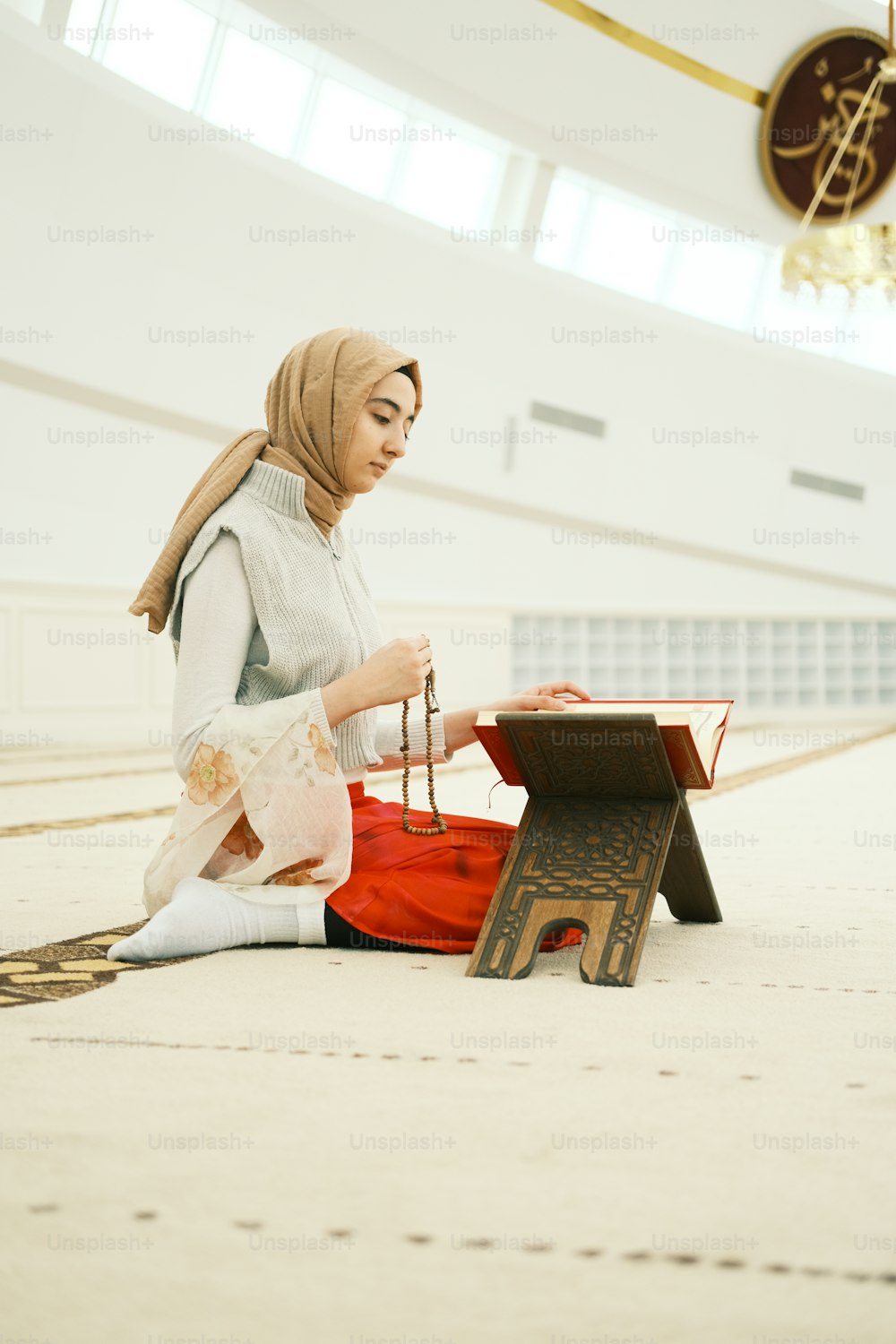 Eine Frau sitzt mit einem Buch auf dem Boden