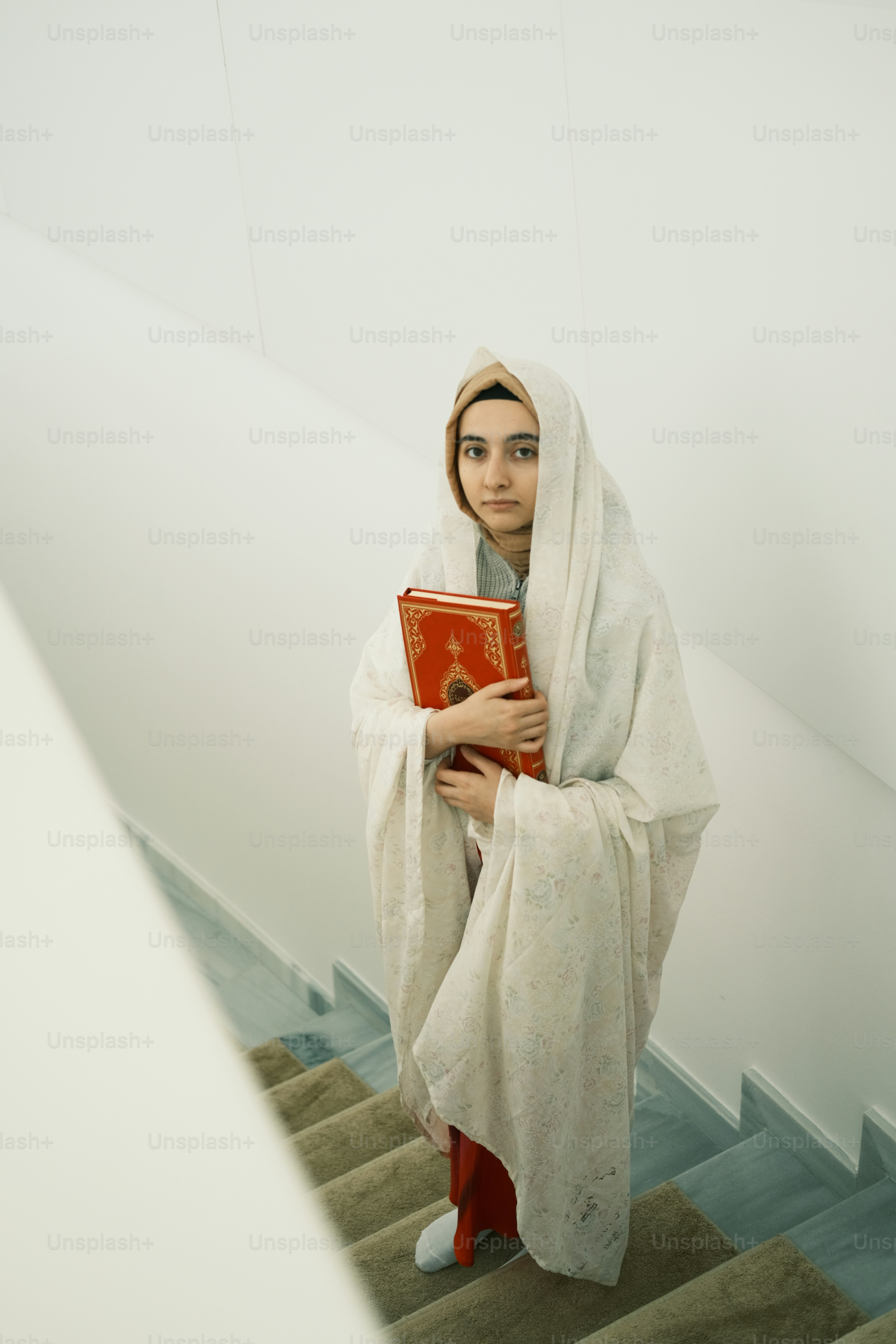 a woman in a white robe holding a red book