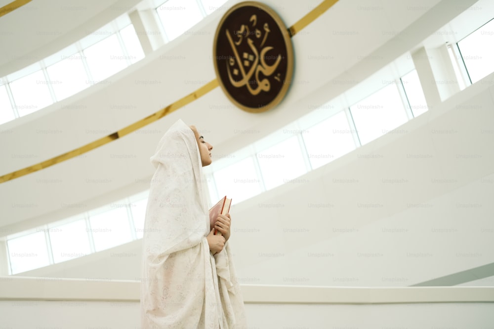 a woman in a white veil standing in front of a clock
