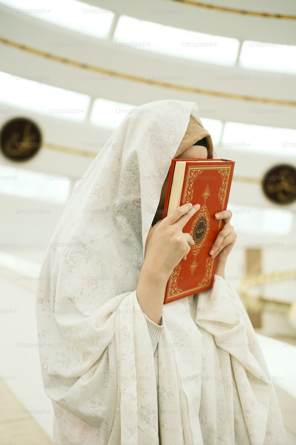 a woman in a white veil holding a red book