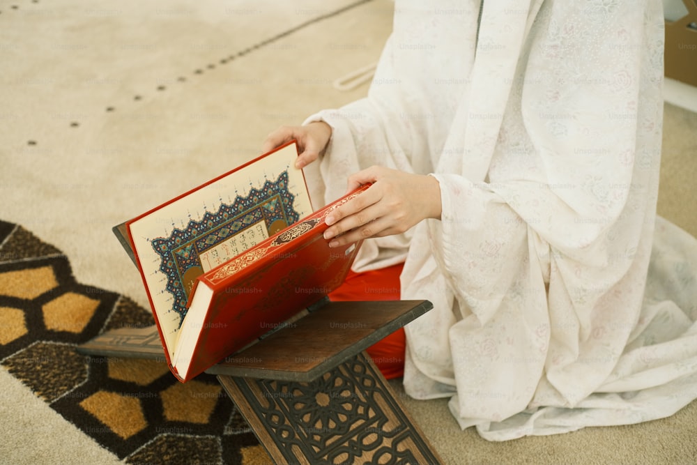 a woman in a white dress is holding a book