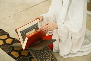 Une femme en robe blanche tient un livre
