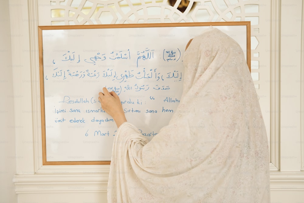 Une femme écrivant sur un tableau blanc dans une pièce