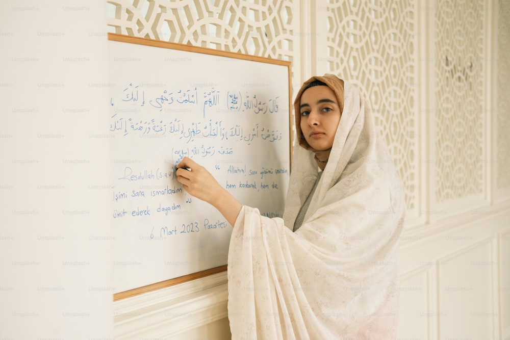 a woman writing on a white board in a room