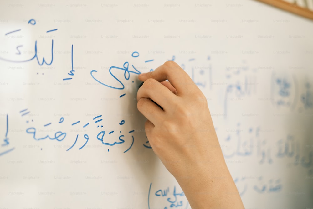 a person writing on a white board with blue writing