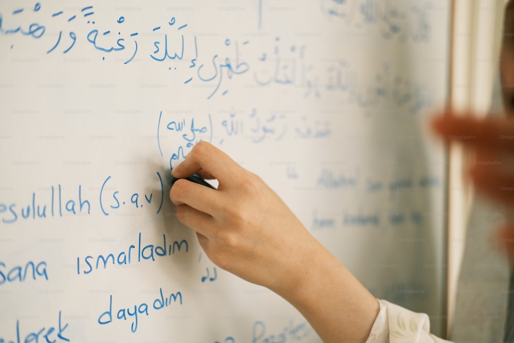 a person writing on a white board with blue writing