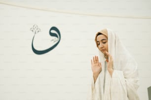 Una mujer con una túnica blanca parada frente a un letrero