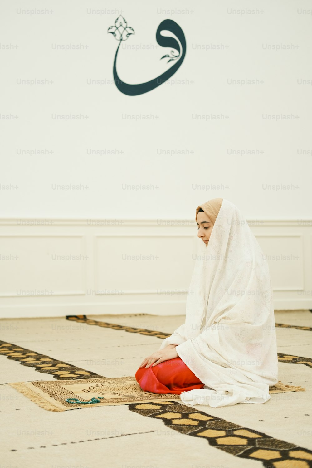 Eine Frau sitzt in einem weißen Kleid auf dem Boden