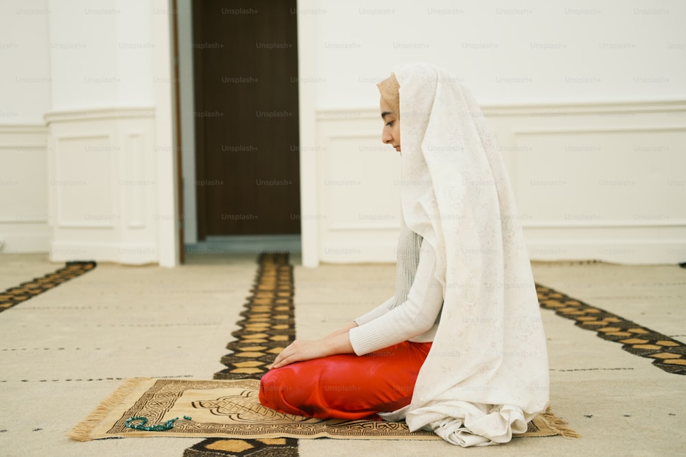 a woman sitting on a rug in a room