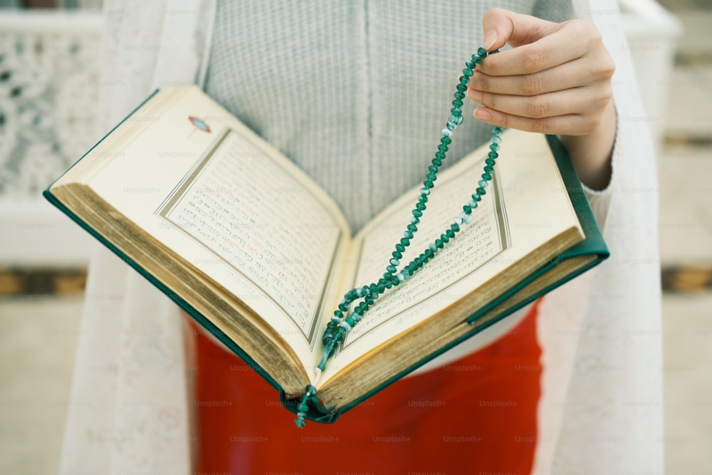 a woman holding a book with a rosary on it