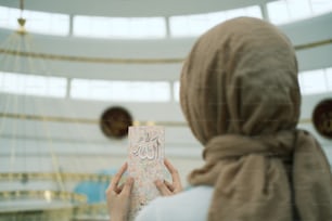 Eine Frau mit Hijab hält ein Buch in der Hand