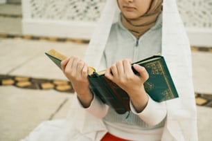 a woman in a white hijab is reading a book