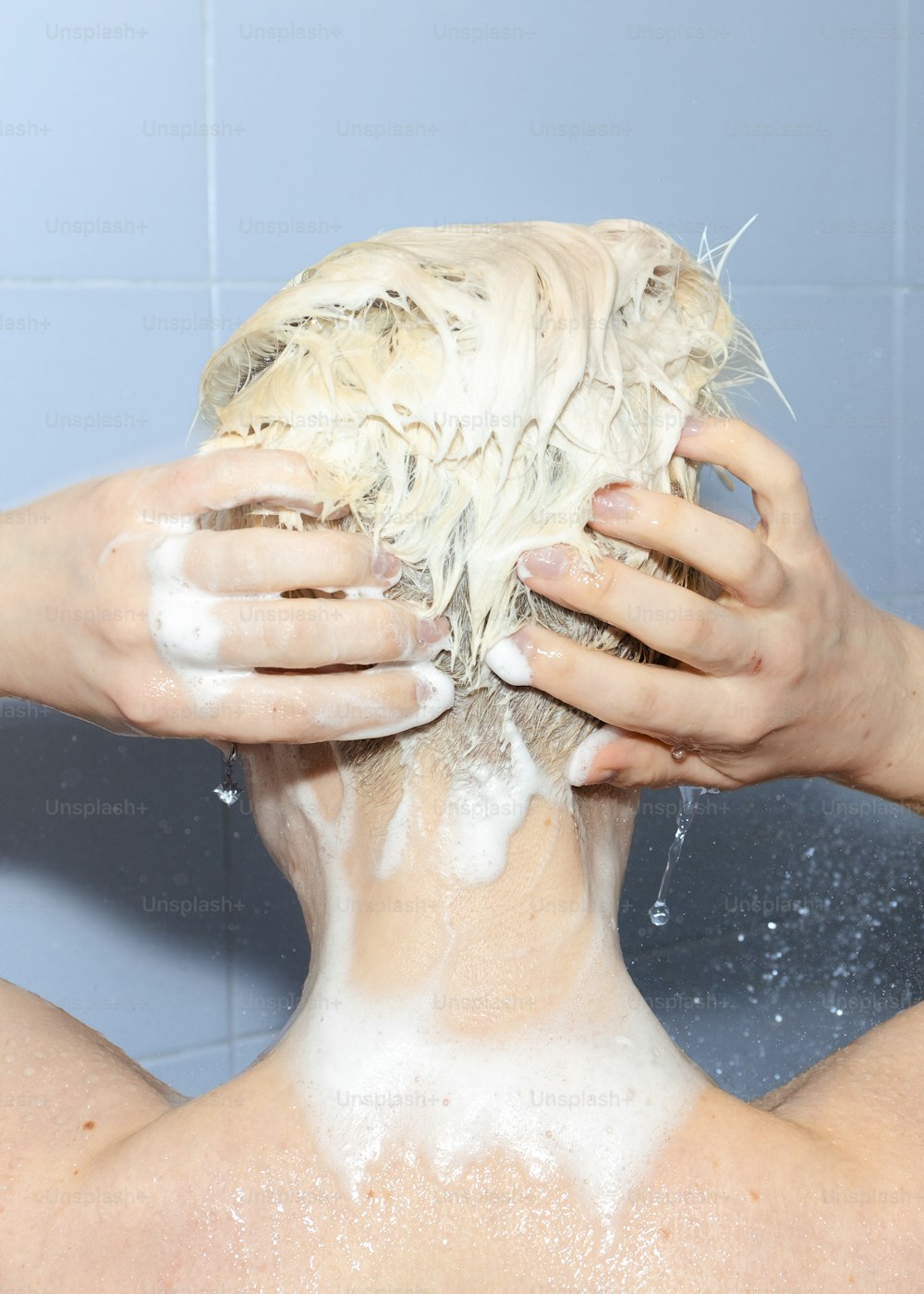 a person washing their hair in a bathtub