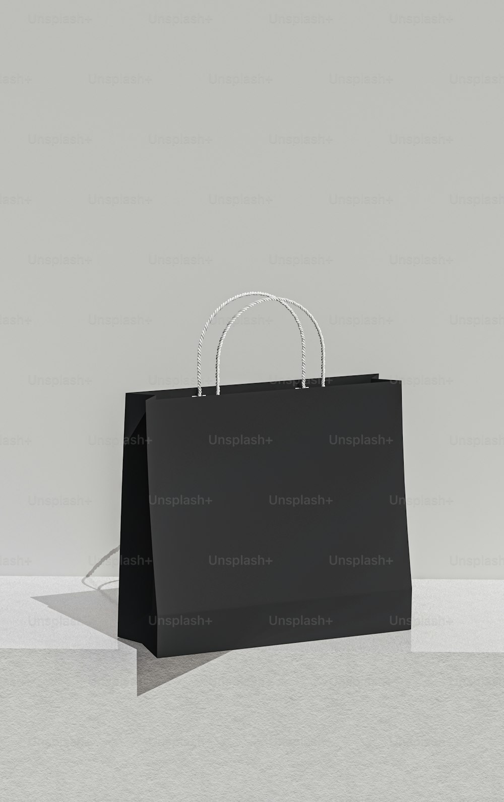 a black shopping bag sitting on top of a white floor