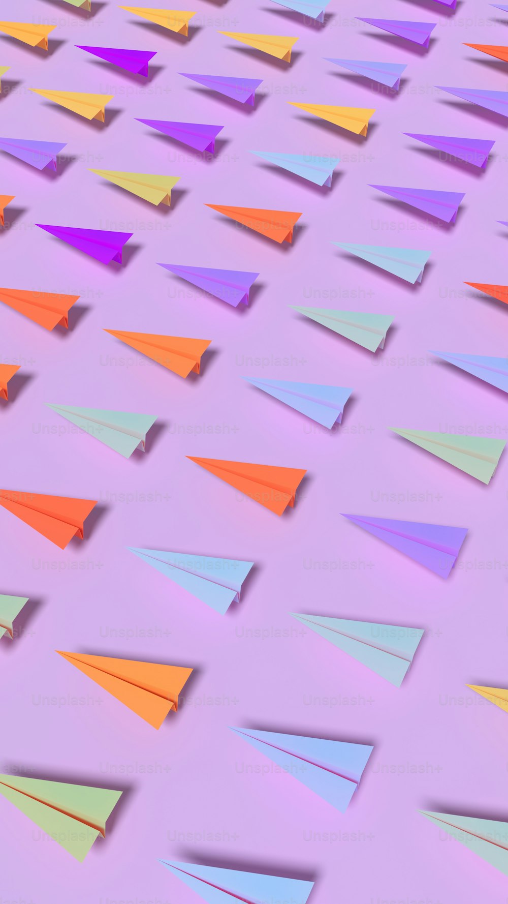Un gruppo di aeroplanini di carta colorati su uno sfondo viola