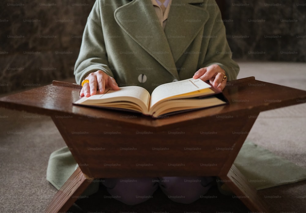 uma mulher em um casaco verde está lendo um livro