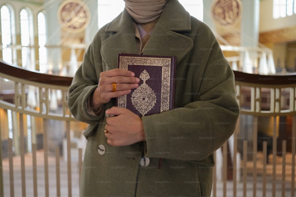 a man in a green coat holding a book