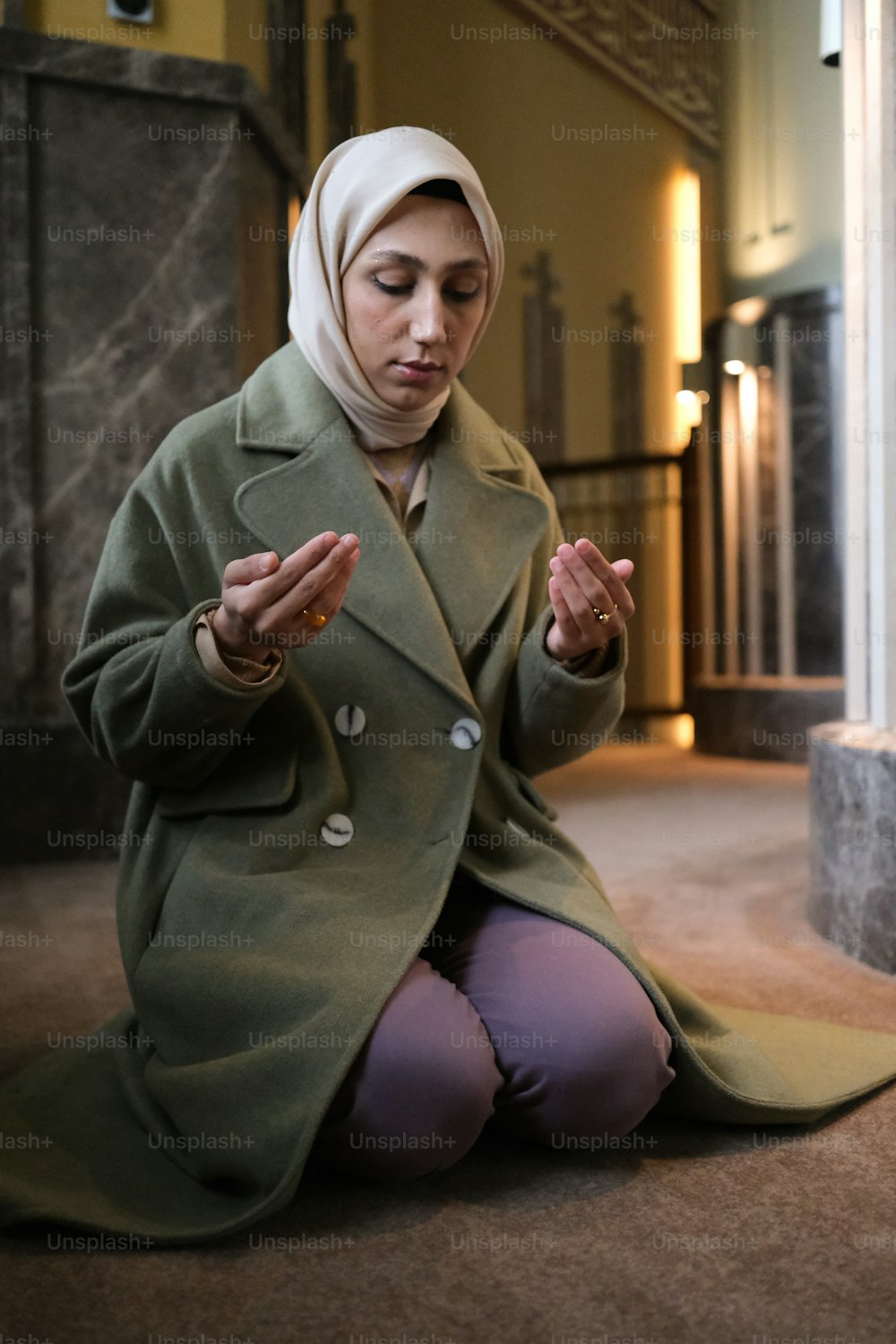 a woman in a green coat sitting on the ground