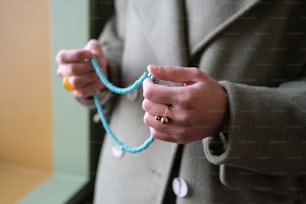 a woman in a coat holding a string of beads