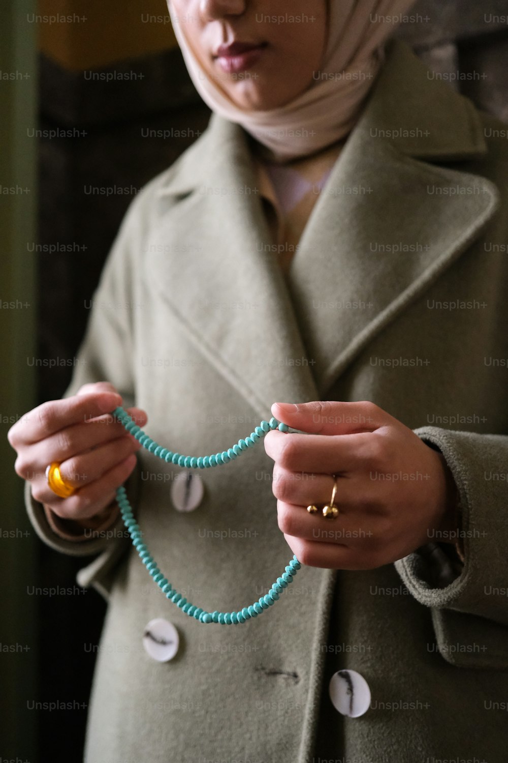 a woman wearing a hijab holding a beaded necklace