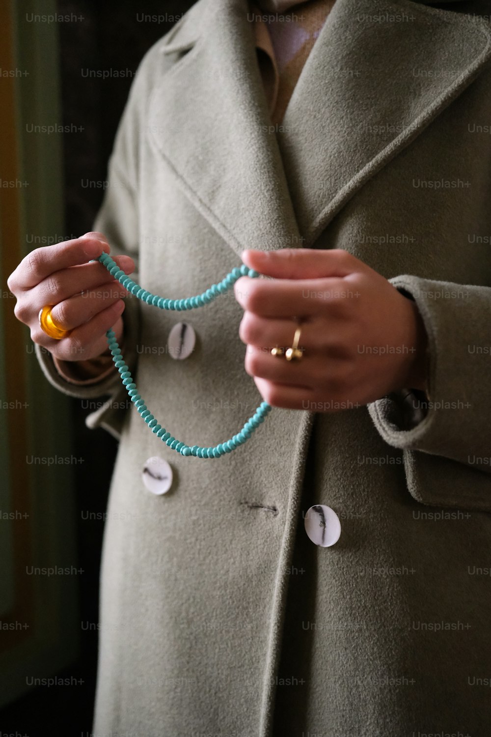 a woman in a coat holding a beaded necklace